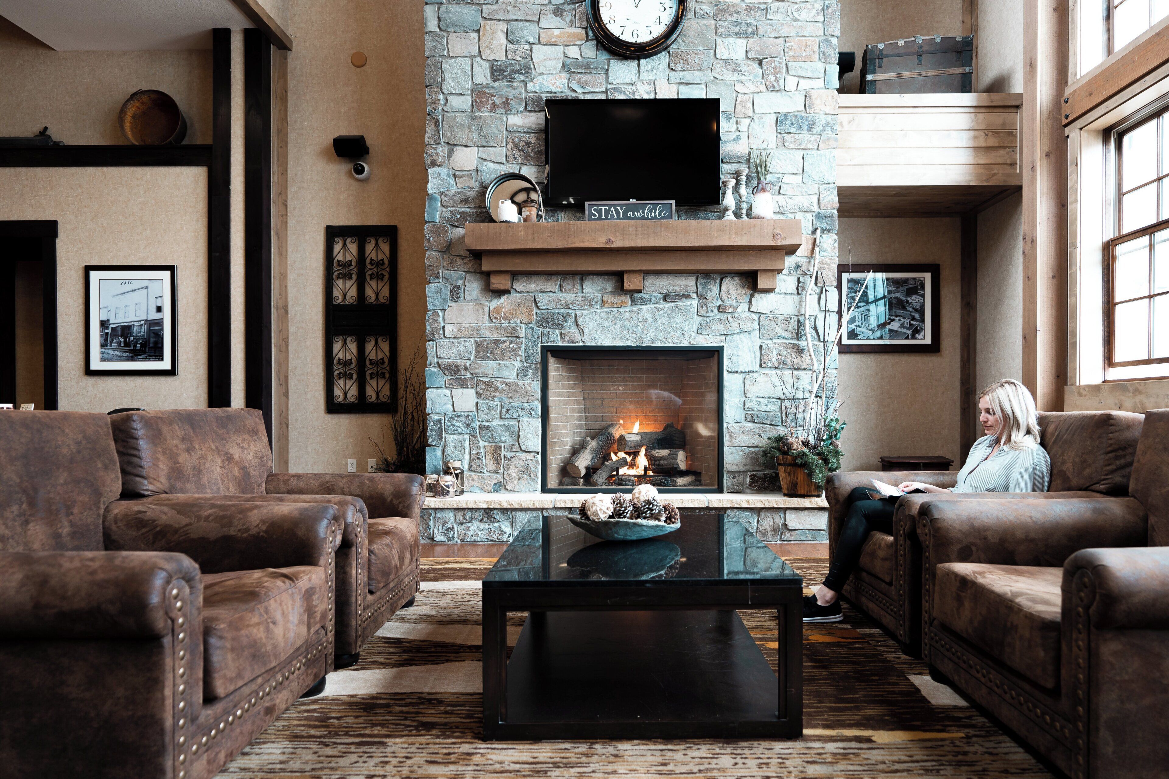 A cozy living room with leather sofas, a stone fireplace, a flat-screen TV, and a coffee table.