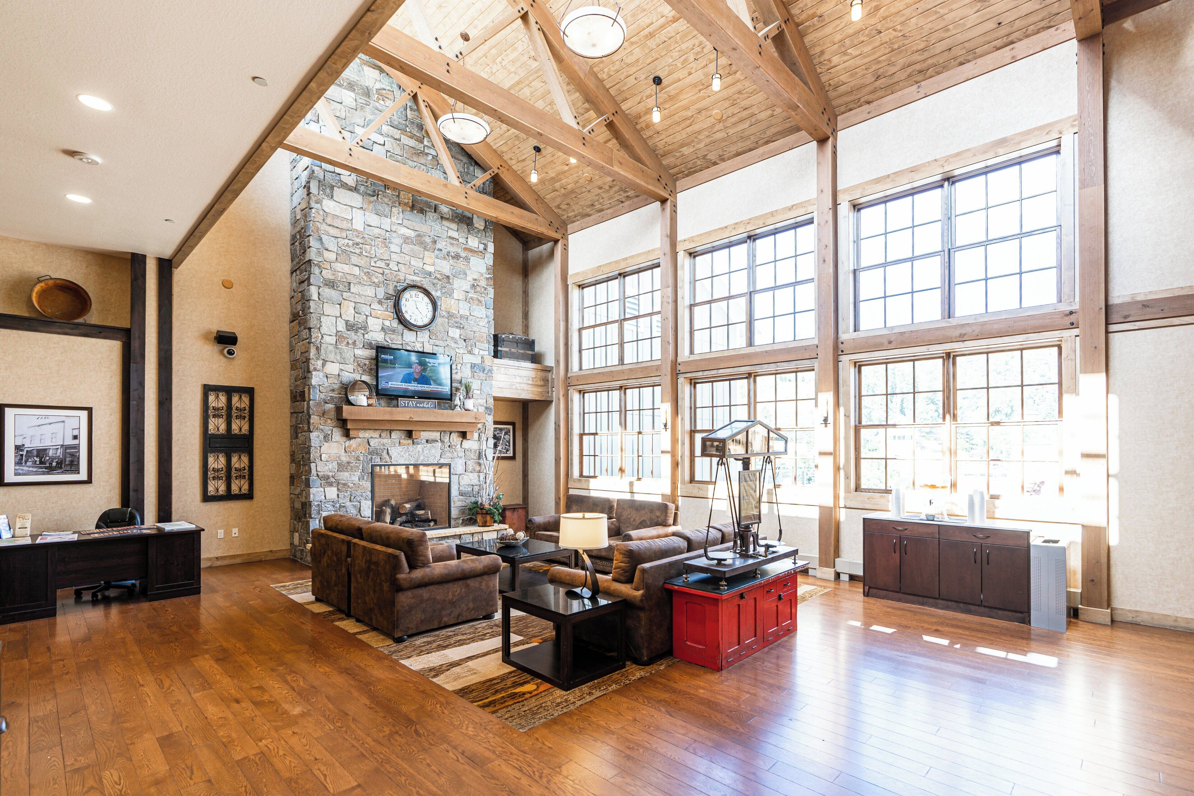 A spacious living area with a stone fireplace, wooden beams, and large windows.