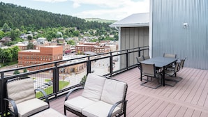 Un balcon avec des meubles d’extérieur, une vue sur une ville et un bâtiment en arrière-plan.