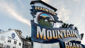 A sign with 'Deadwood Mountain Grand' written on it, with a mountain graphic and a cowboy hat.