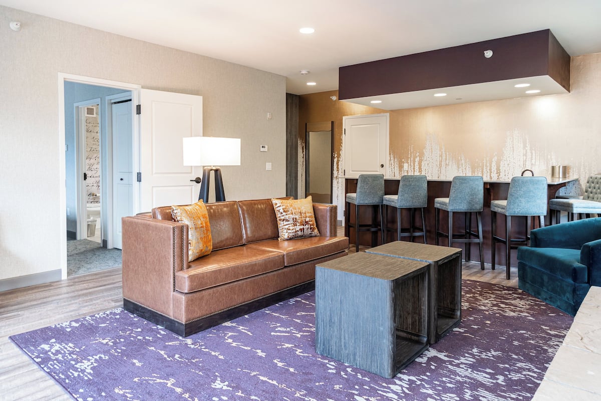 A modern hotel lobby with a leather sofa, a bar area, and a reception desk.