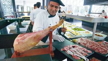 A chef preparing a large piece of meat at a buffet.