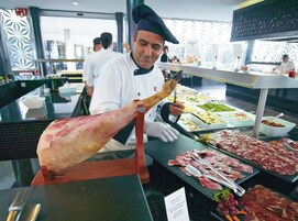A chef preparing a large piece of meat at a buffet.
