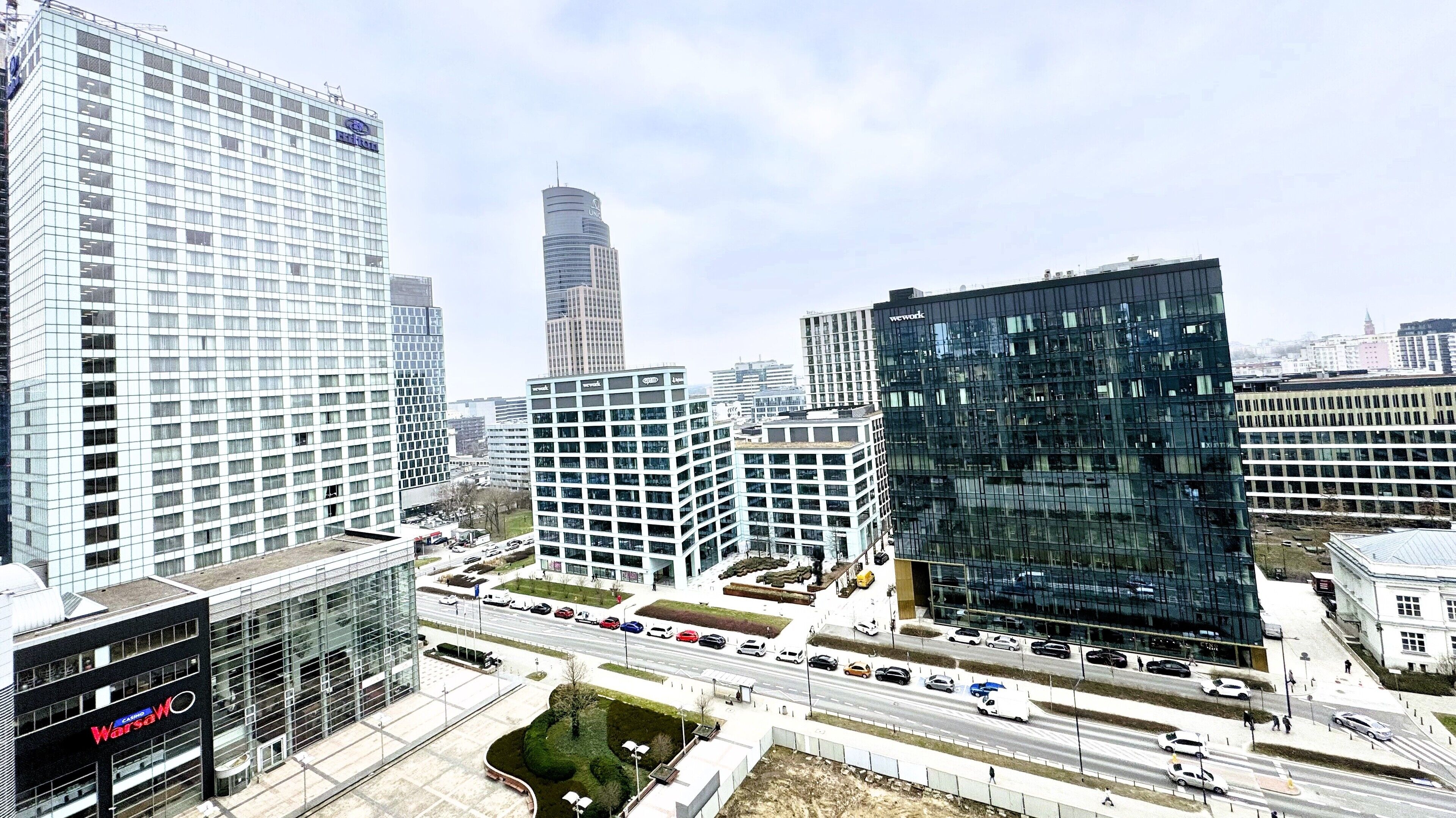 Uma área urbana moderna com edifícios altos, incluindo um imponente arranha-céu de vidro e um casino.