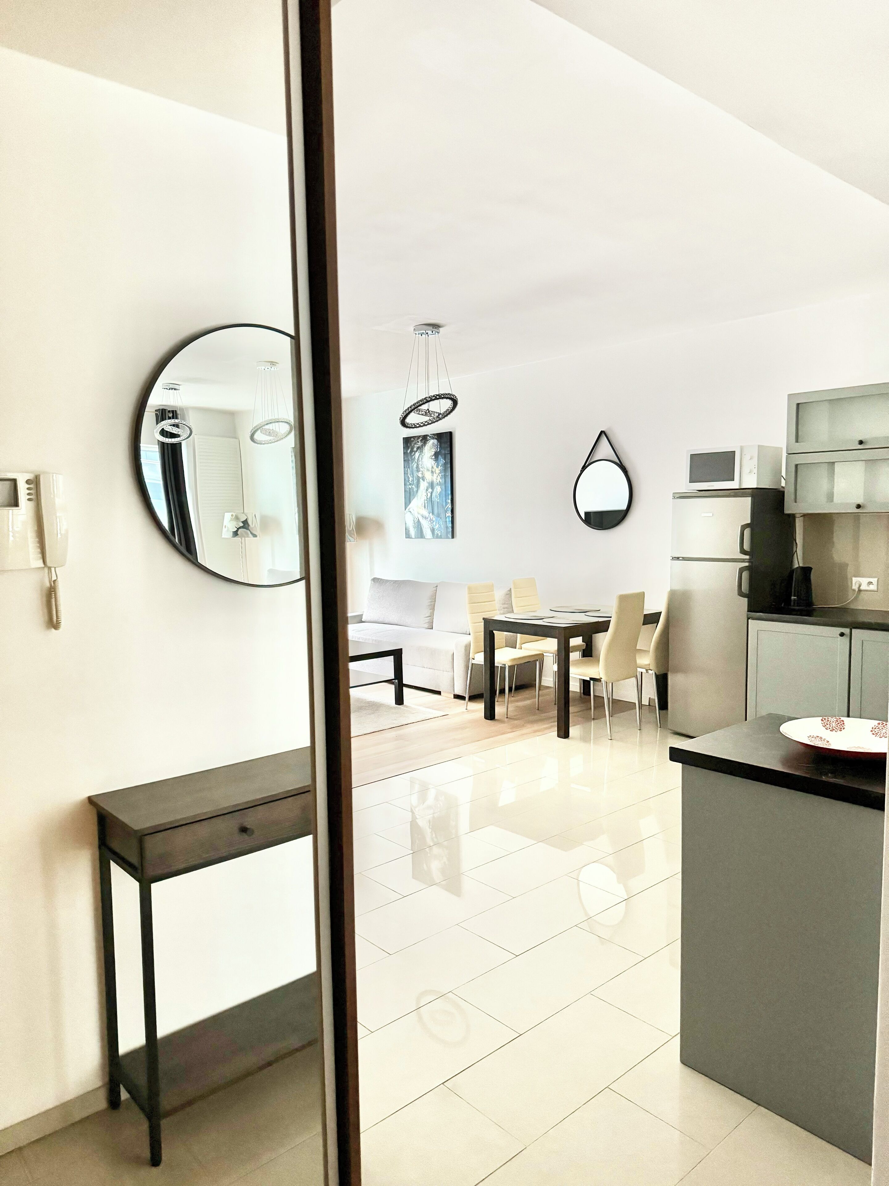 A modern kitchen with a dining area, a large mirror, and a light fixture.