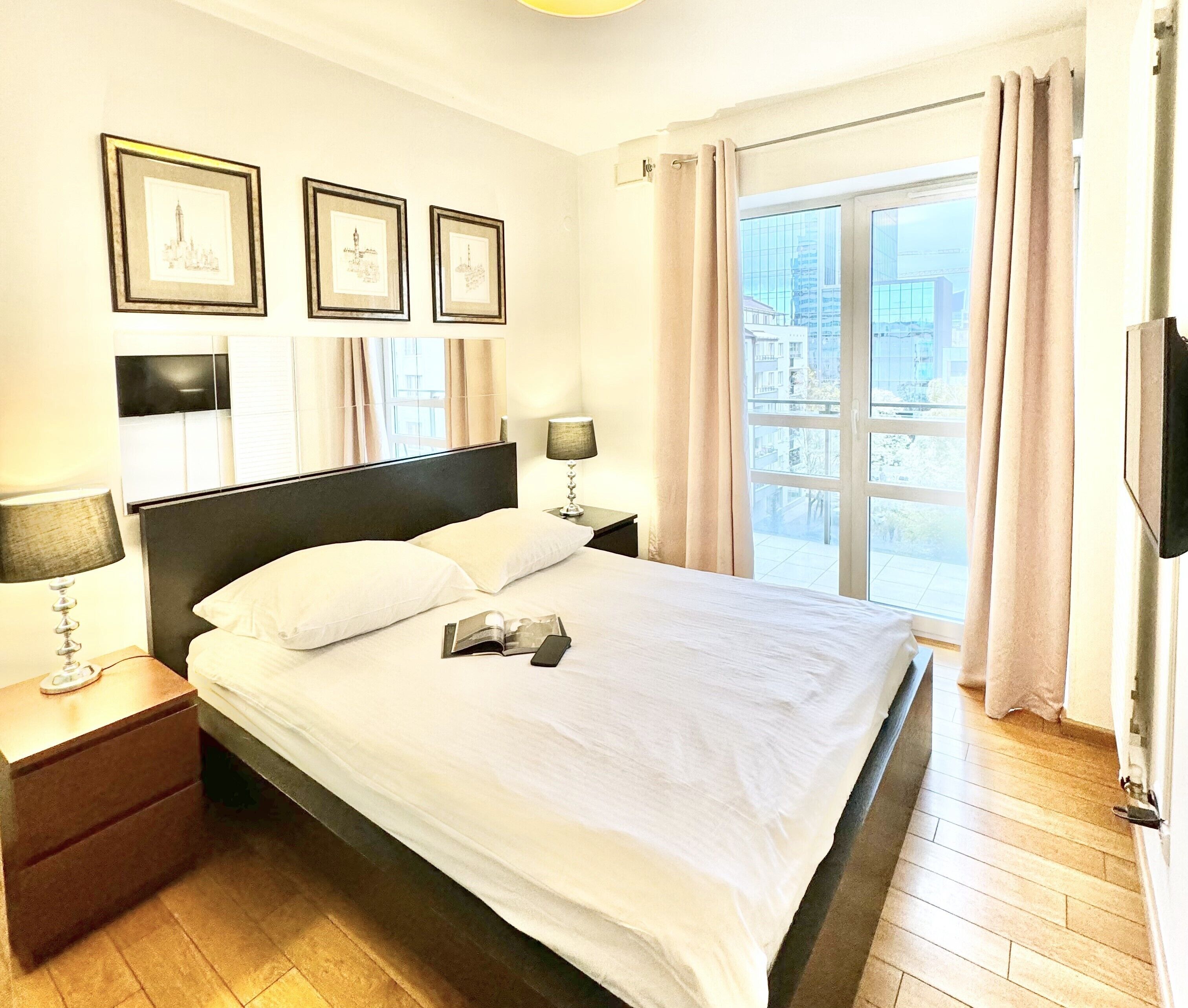 A hotel room with a large bed, two bedside tables, a lamp, and framed pictures on the wall.