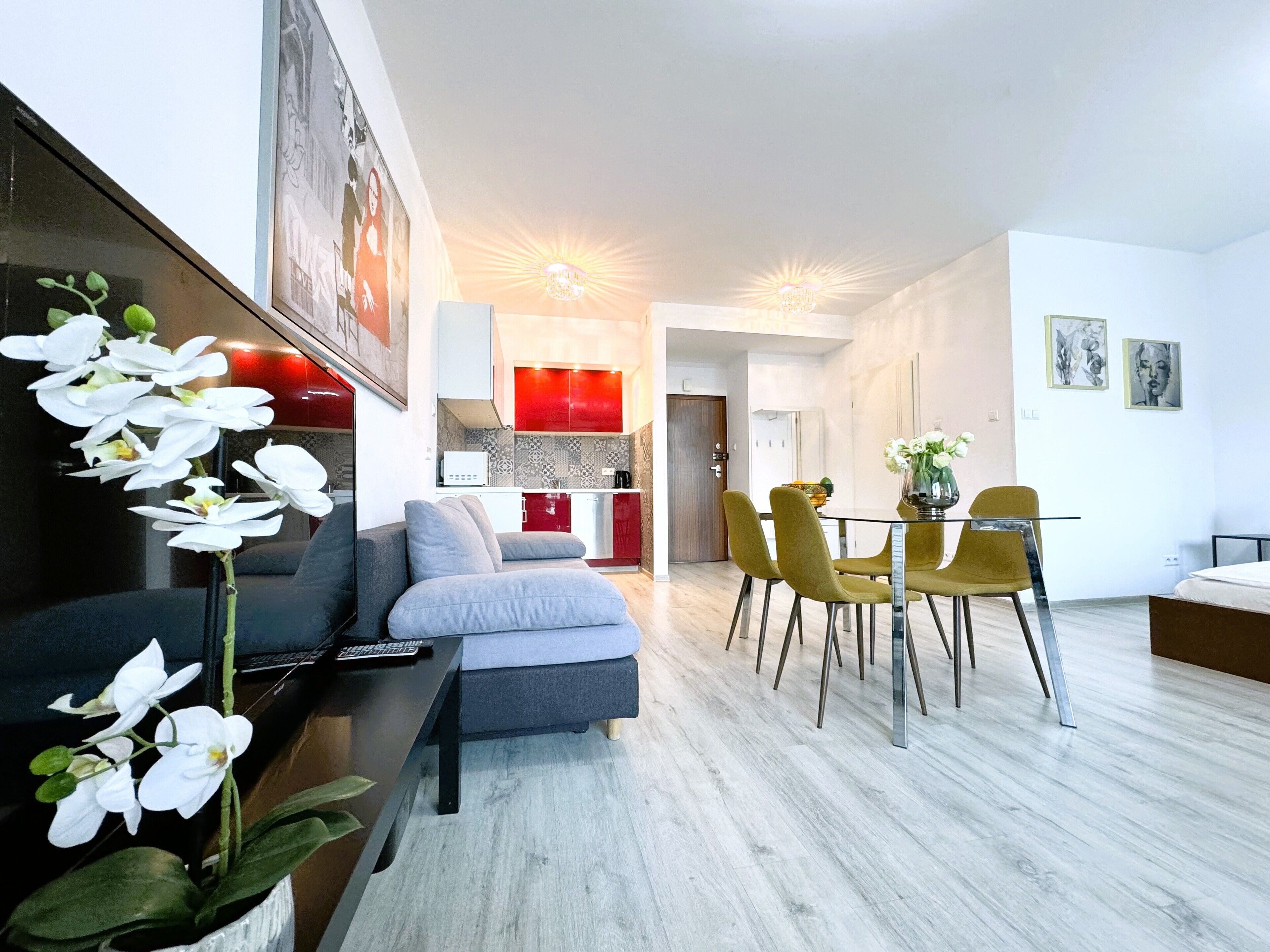 A modern living room with a sofa, a dining table with chairs, and a kitchen area in the background.