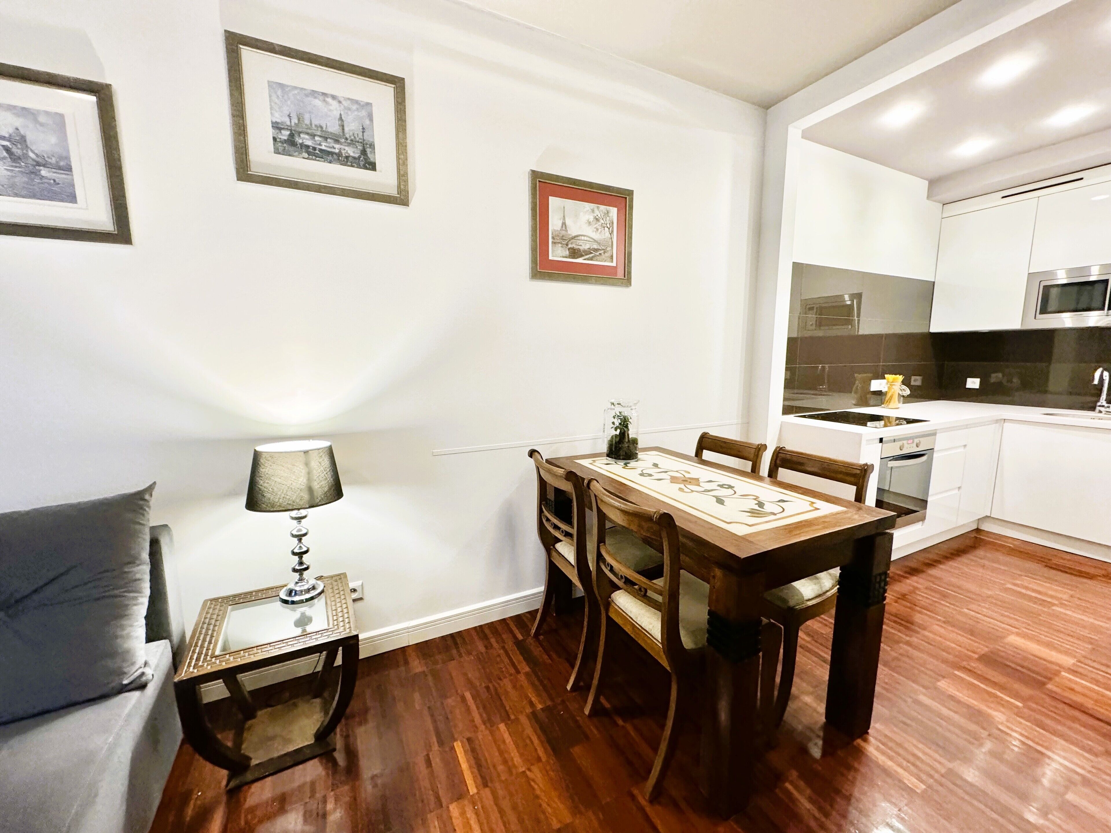 A compact living space with a dining table, chairs, a lamp, and a sofa.