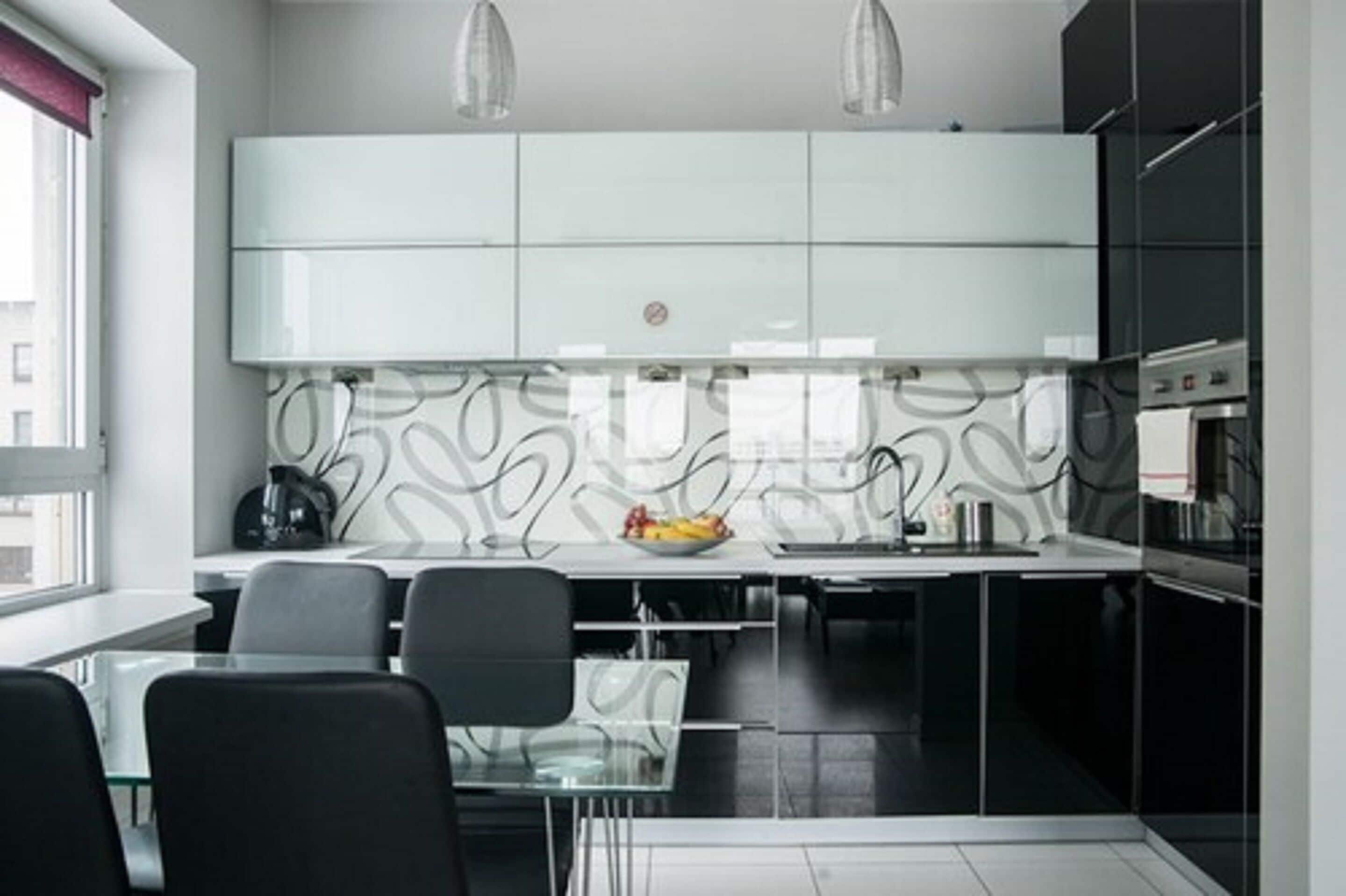 Una cocina moderna con armarios blancos, una mesa de comedor de cristal y dos lámparas colgantes.