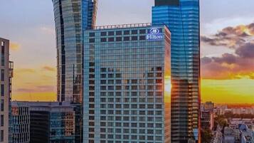 A Hilton hotel building with a modern glass facade, surrounded by other high-rise buildings.