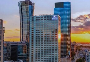 Hilton-hotellin rakennus, jossa on moderni lasijulkisivu, ja sen ympärillä on muita korkeita rakennuksia.