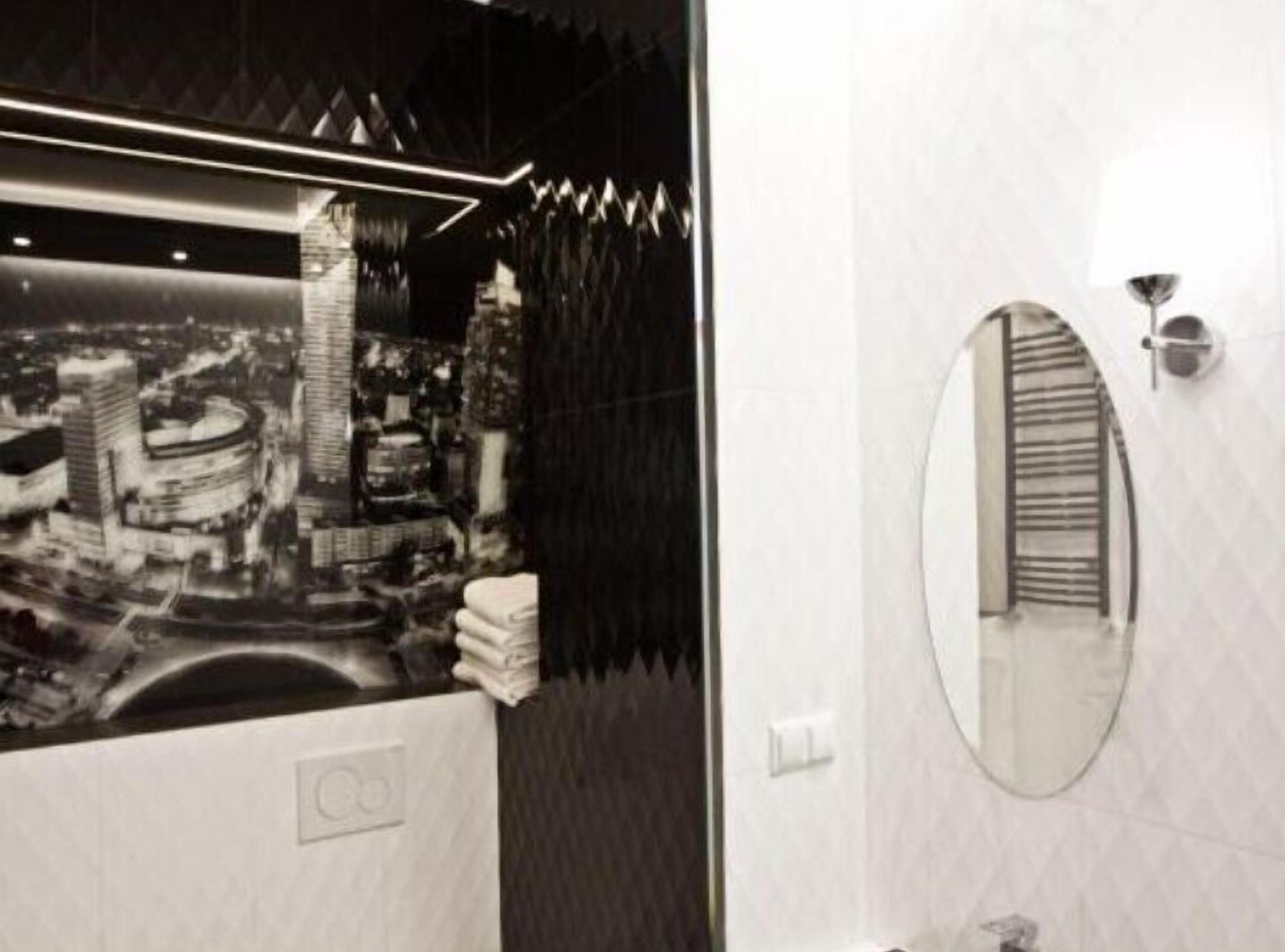 A modern bathroom with a cityscape view, a round mirror, and a unique black and white striped wall design.