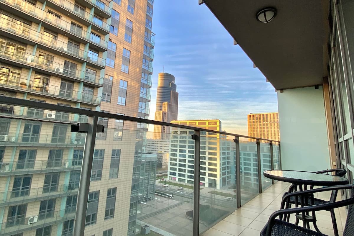 Un balcon doté d’une balustrade en verre donnant sur un paysage urbain.