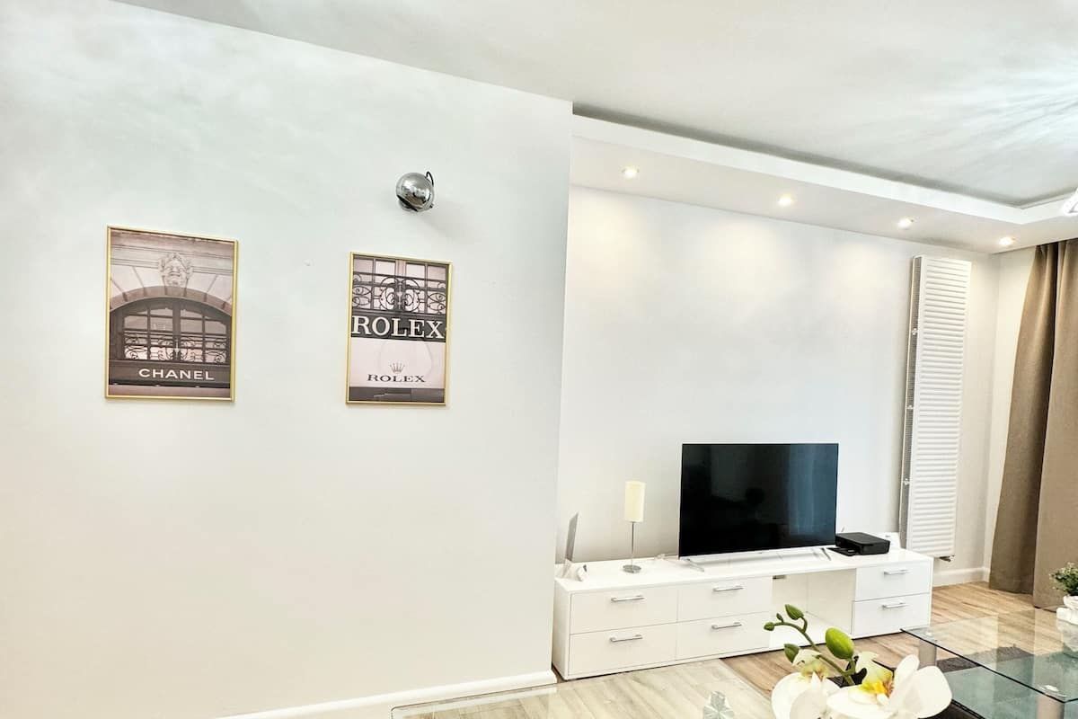 Un salon moderne avec une table basse en verre, un canapé blanc et un téléviseur à écran plat.