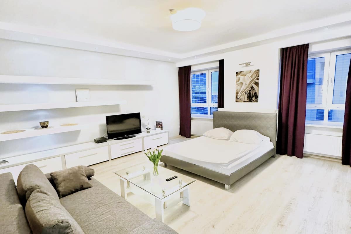 Une chambre d’hôtel moderne équipée d’un canapé, d’un lit, d’une télévision, d’une table basse et offrant une vue sur la ville.