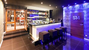 A modern bar area with a counter, bar stools, and a variety of bottles.