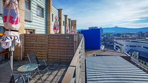 A rooftop terrace with a view of the city, a brick wall, and a blue fence.