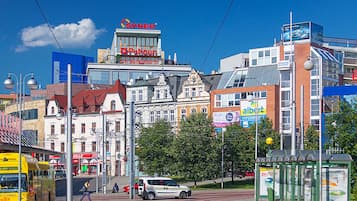 A city street with a mix of modern and historic buildings, a tram, and a bus.