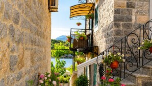 Un escalier en pierre menant à un balcon agrémenté de plantes en pot et offrant une vue sur un lac.