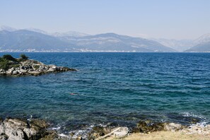 A coastal landscape with rocky shores and a view of distant mountains. - Sea Residence Kristina Romantica (Gosici)