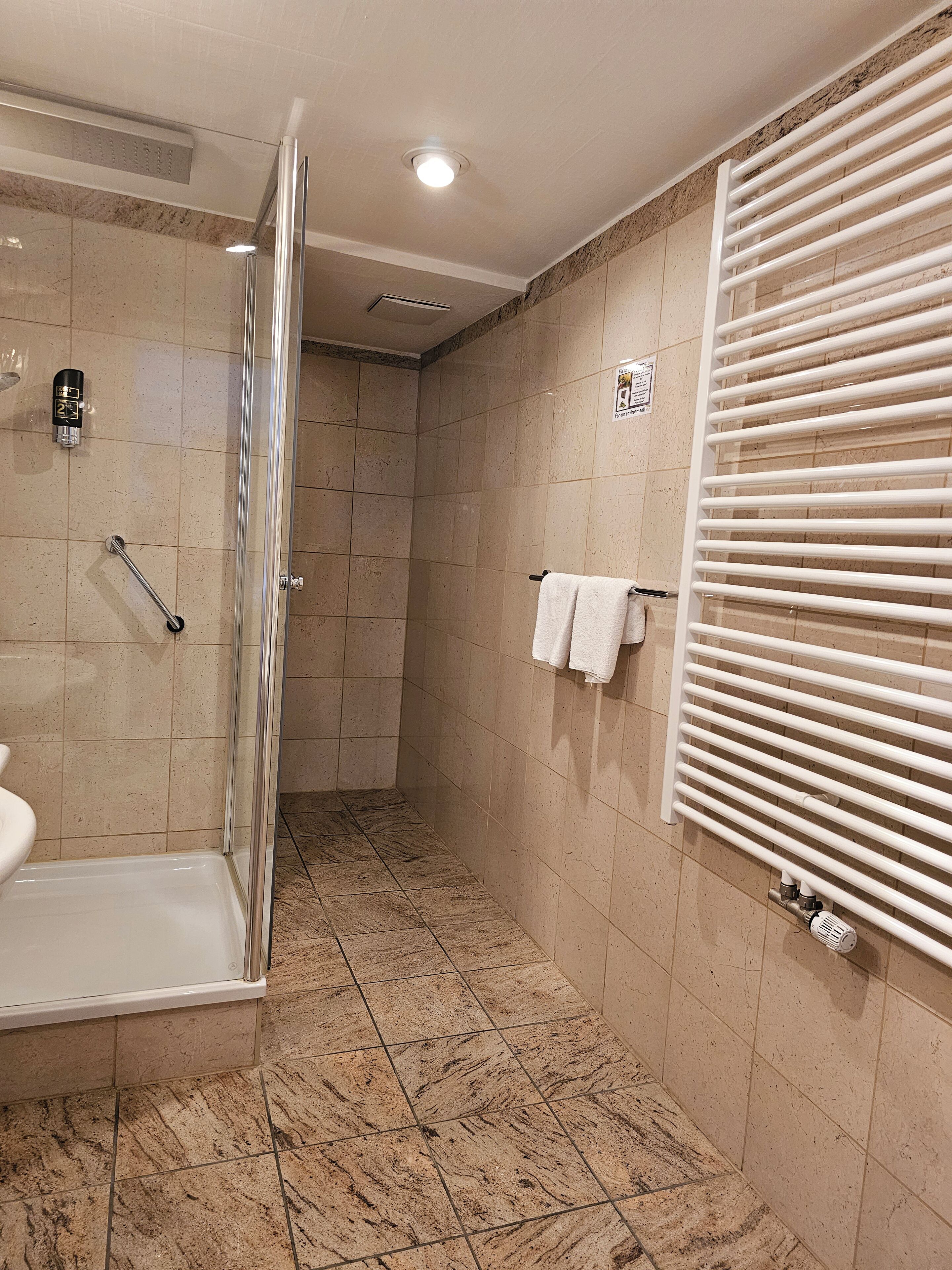 Une salle de bain avec une douche, des toilettes et un porte-serviettes.