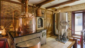 A brewery with copper brewing equipment, a wooden interior, and a view of the outside through a door.