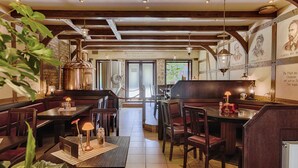 A restaurant with wooden beams, tiled floors, and tables with red cushions.