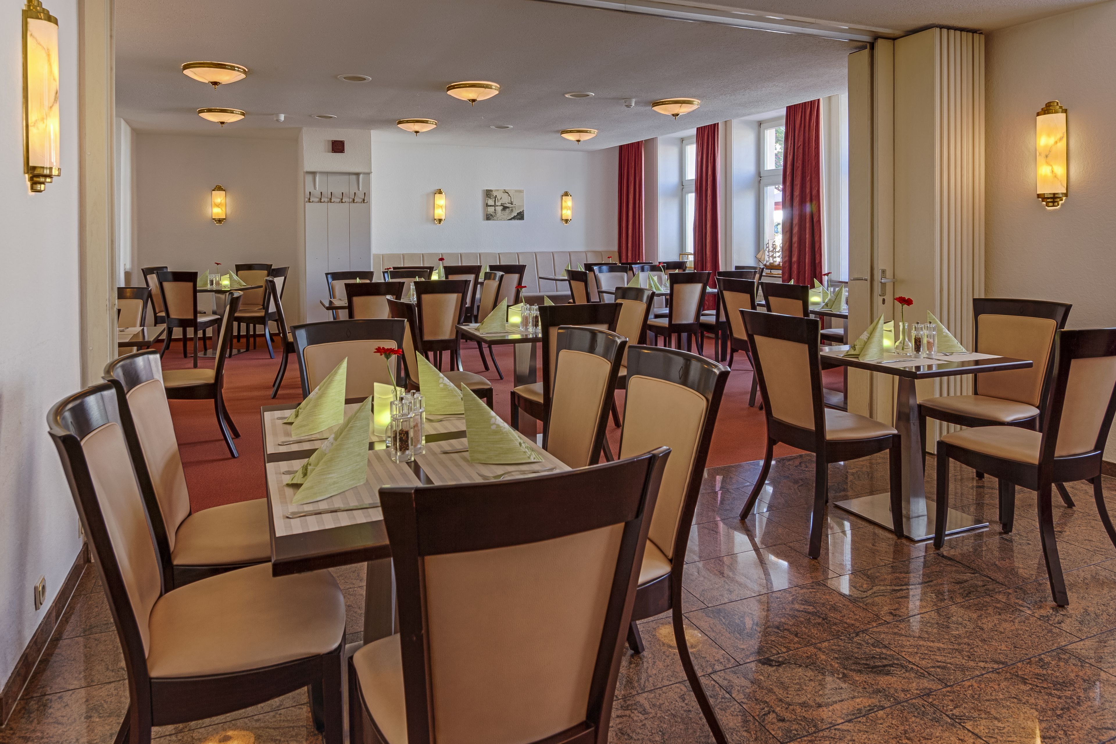 A spacious restaurant with multiple tables and chairs, well-lit by ceiling lights, and featuring a clean, modern design.