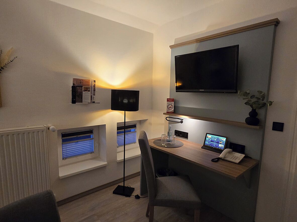 A modern office space with a desk, computer, and a mounted TV.