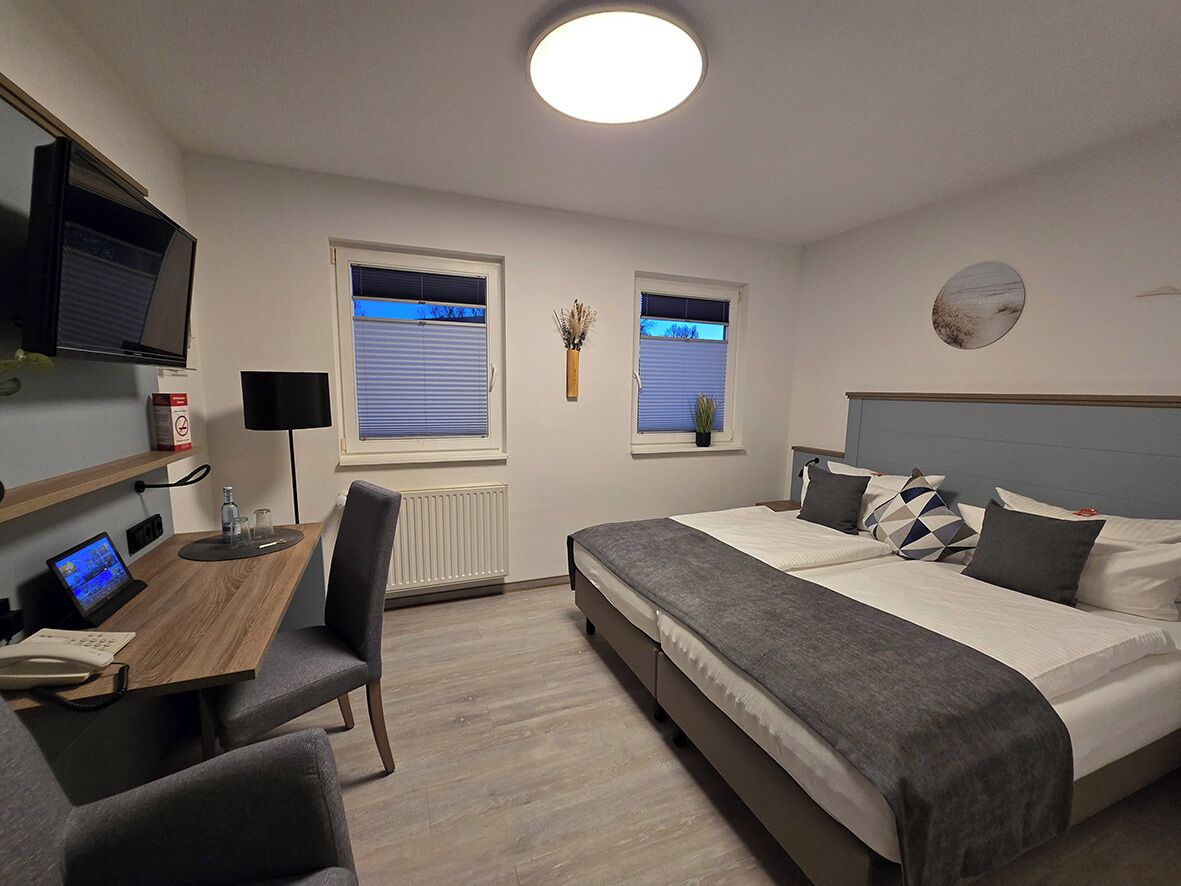 A modern hotel room with a bed, desk, and TV.