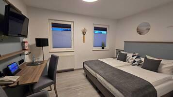 A modern hotel room with a bed, desk, and TV.