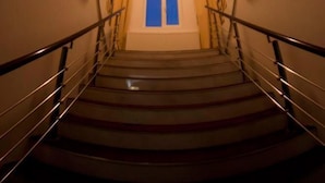 A staircase with a handrail, a light fixture at the top, and a window with curtains at the bottom. - Visconti Residence (Bucharest)