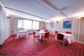 A hotel room with a red patterned carpet, white curtains, and a dining area with tables and chairs. - Visconti Residence (Bucharest)