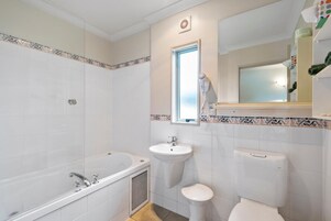 Un baño con bañera, lavamanos, inodoro y ventana.