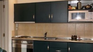 A modern kitchen with dark cabinets, a microwave, and a stainless steel oven.