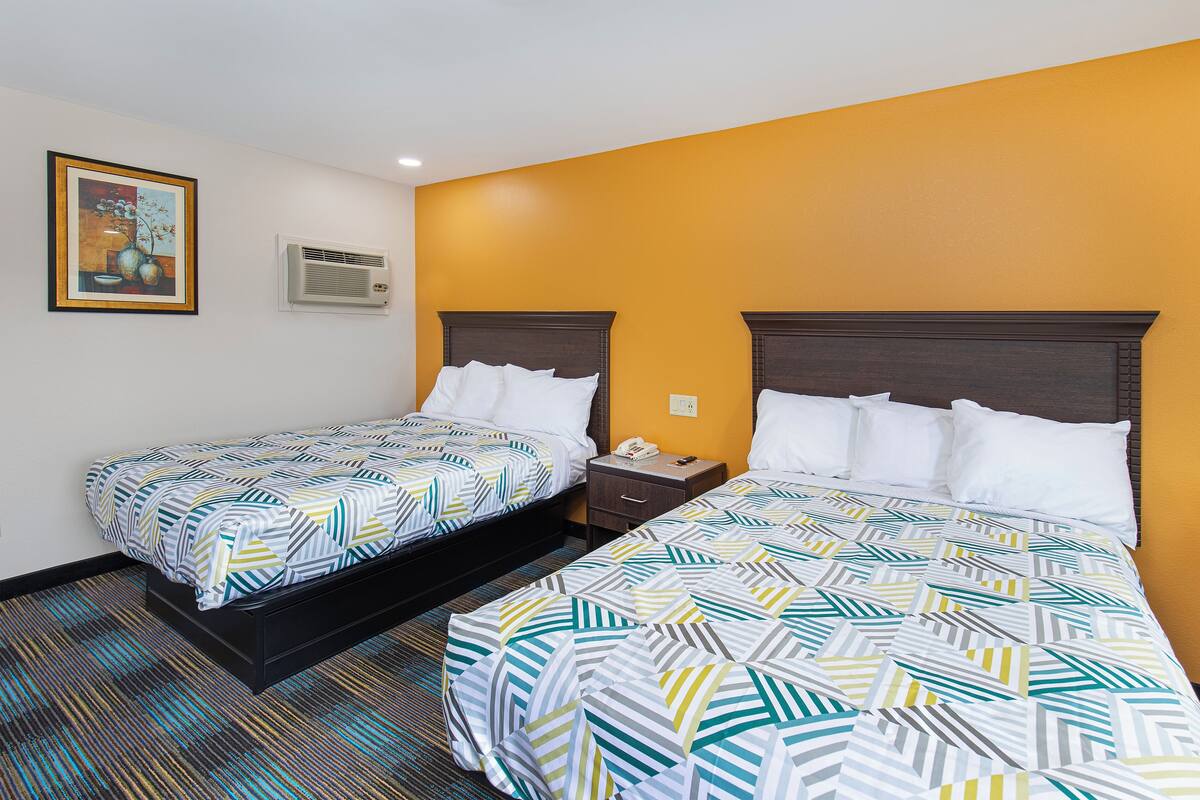 Quarto de hotel com duas camas, um quadro na parede e um aparelho de ar condicionado.