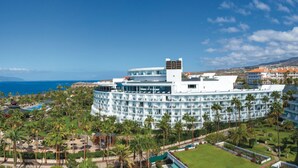 A resort with a circular building, a pool, and palm trees. - Hotel Riu Palace Tenerife (Adeje)