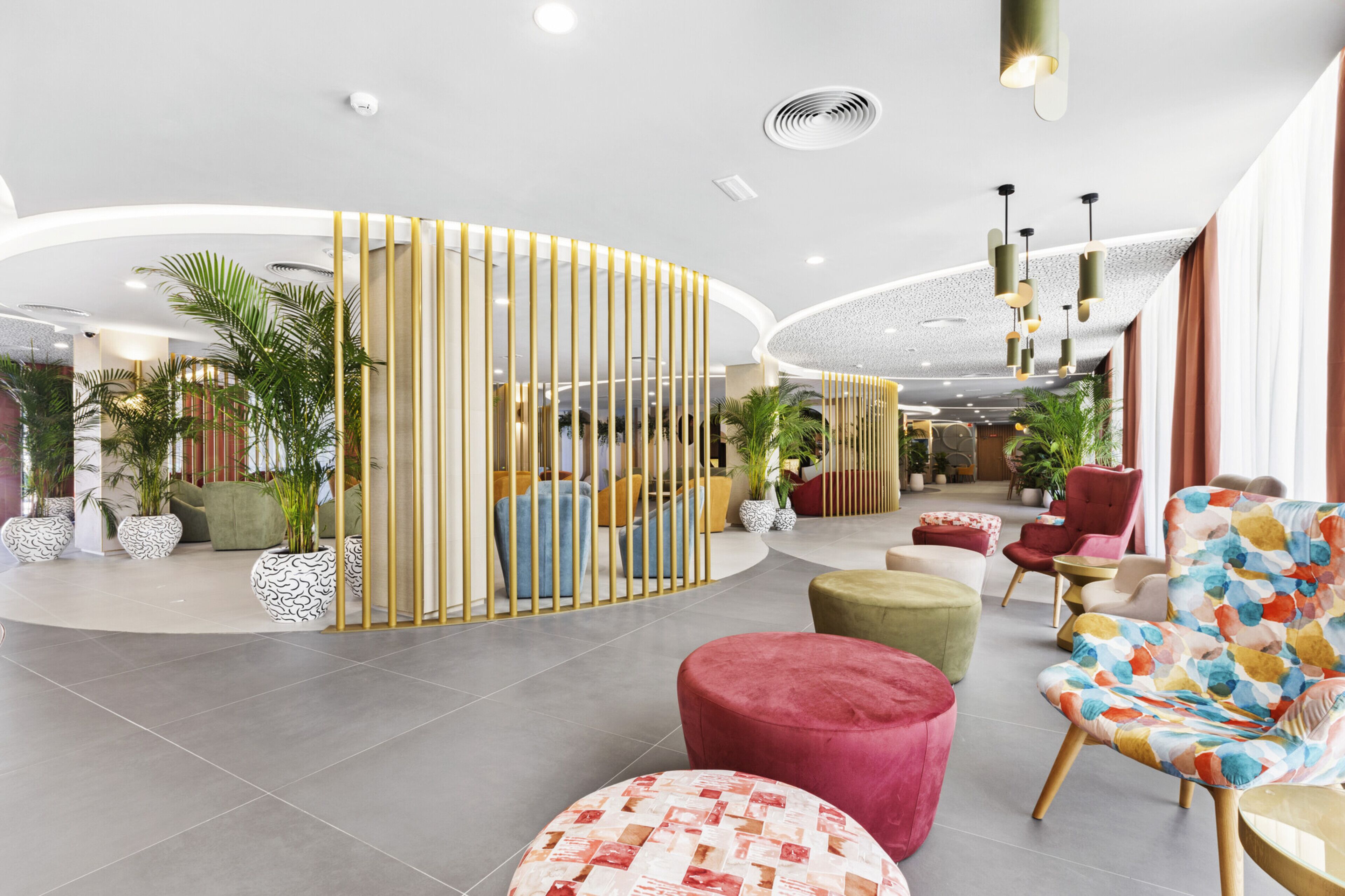 A modern lobby with a curved seating area, a decorative partition, and various seating options including a colorful armchair and ottomans.