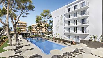 Una piscina al aire libre, sombrillas, sillones reclinables de piscina