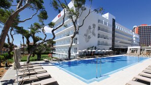 Un hotel con piscina, sillas de descanso y vistas del entorno.