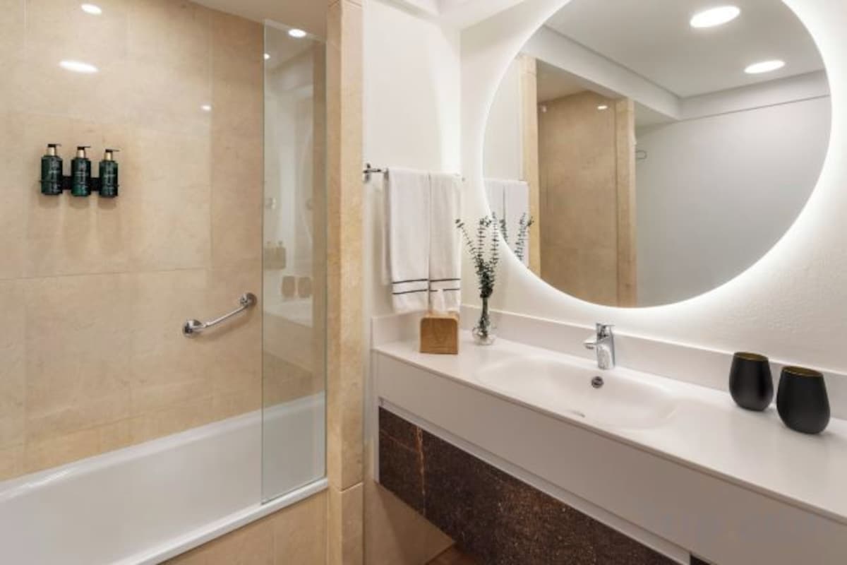 A modern bathroom with a glass-enclosed shower, a white vanity with a large mirror, and a marble countertop.