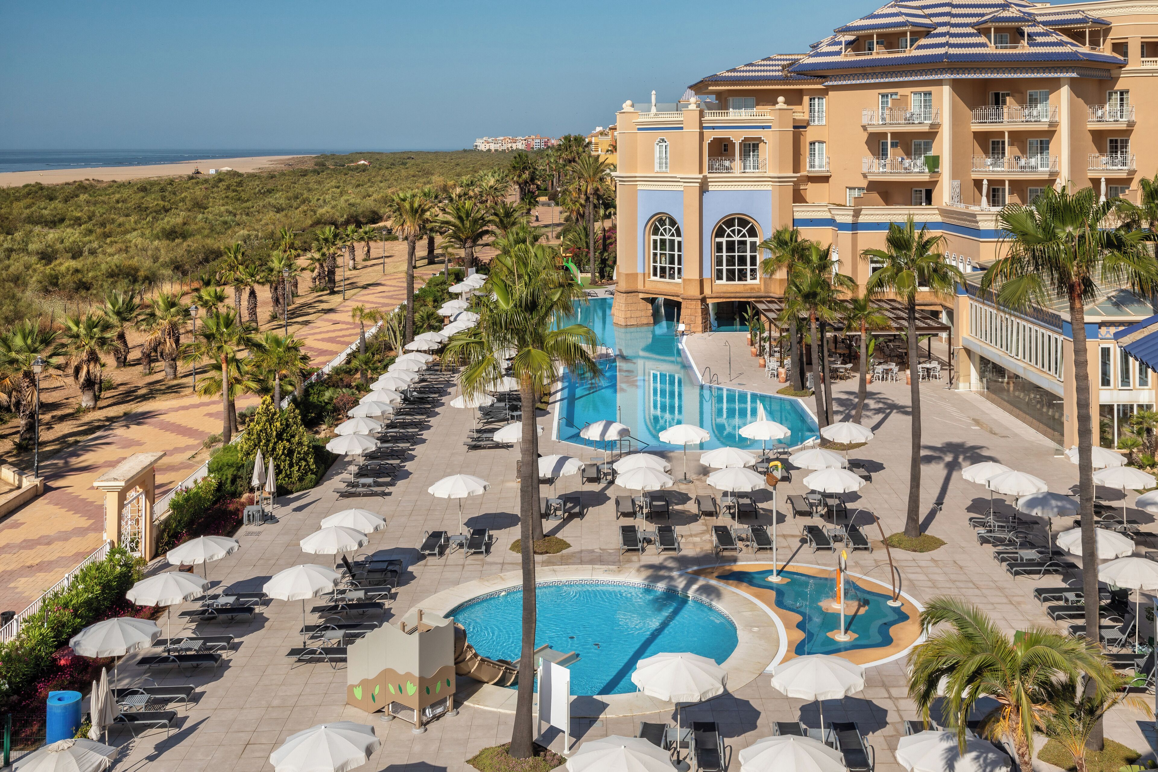 Un resort con un amplio espacio de piscina, numerosas tumbonas y sombrillas.