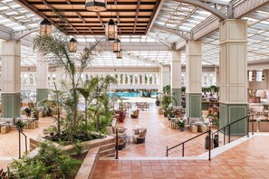 A spacious indoor area with a pool, seating areas, and potted plants. - Meliá Isla Canela (Ayamonte)