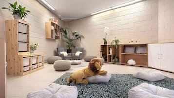 Ein gemütliches Zimmer mit einem weichen Löwenkuscheltier, Stauraumeinheiten, einem grauen Sessel und einem Bücherregal.
