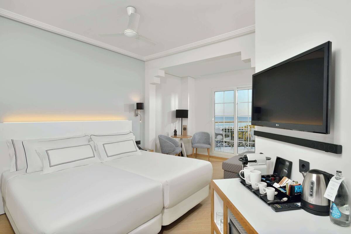 Une chambre d’hôtel moderne dotée d’un grand lit, d’une télévision à écran plat, d’un coin café et d’un balcon avec vue.