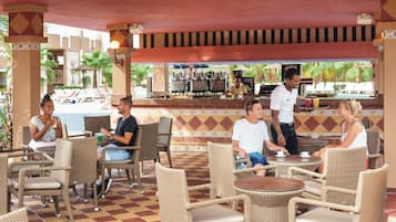 A covered outdoor seating area with wicker furniture and a bar.
