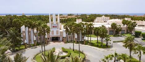 A resort with a central building featuring a prominent tower and the name "RIU" on its facade.