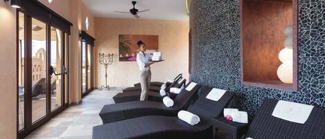 A spa area with reclining chairs, a reception desk, and a wall with a mosaic pattern.
