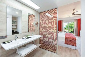 A modern bathroom with a large mirror, a white sink, and a patterned wall.