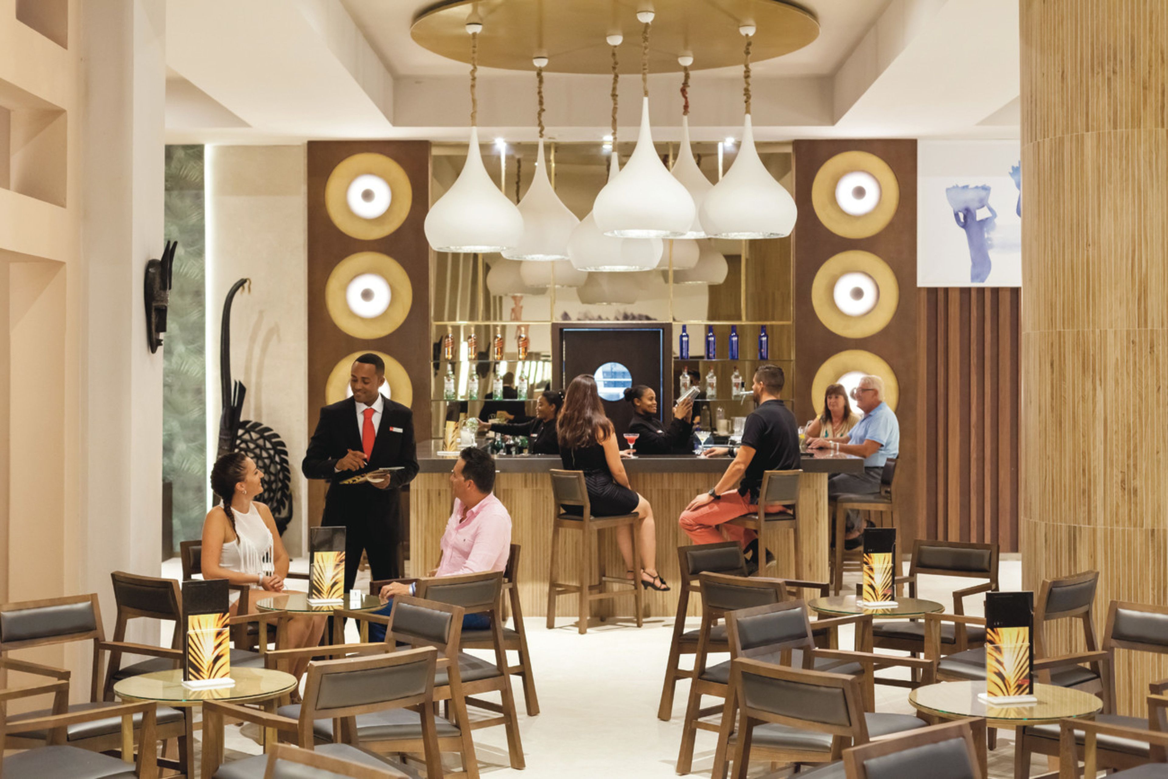 A modern bar area with multiple seating options, including bar stools and round tables.